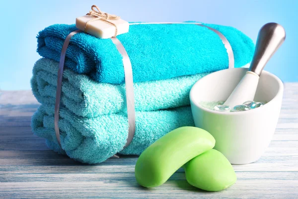 Still life with set of tied towels on wooden surface and light colorful background — Stock Photo, Image