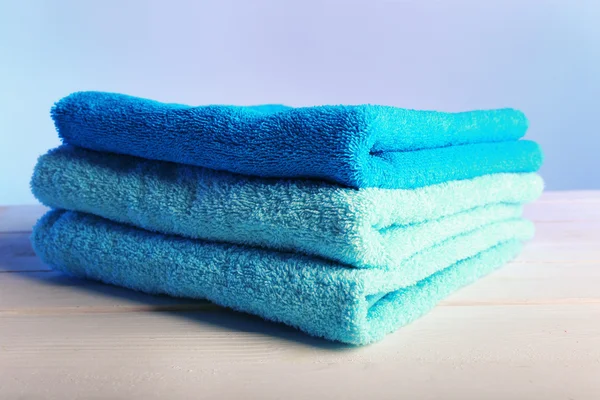 Διπλωμένες πετσέτες στο ξύλινο τραπέζι και ανοιχτό φόντο πολύχρωμο — Φωτογραφία Αρχείου