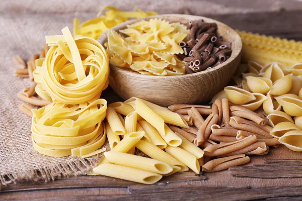 Diferentes tipos de pasta en mesa de madera rústica —  Fotos de Stock