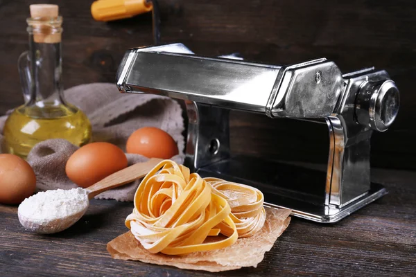 Voorbereiding van pasta door Pastamachine op rustieke houten achtergrond — Stockfoto