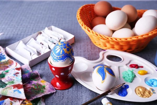 Painting Easter eggs on colorful tablecloth background — Stock Photo, Image