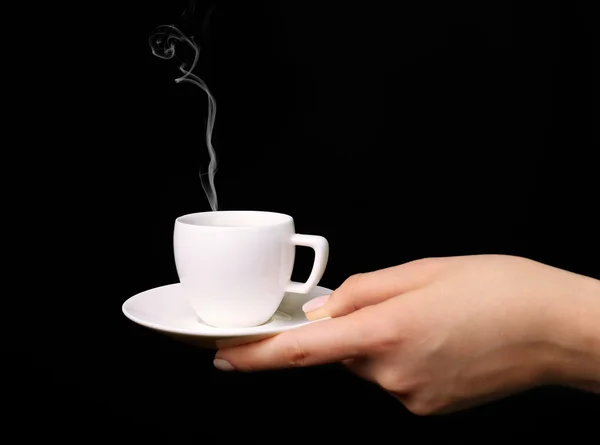 Kvinnlig hand innehav kopp kaffe med tefat på svart bakgrund — Stockfoto