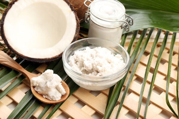 Coconut with leaf and coconut oil in jar on wooden background