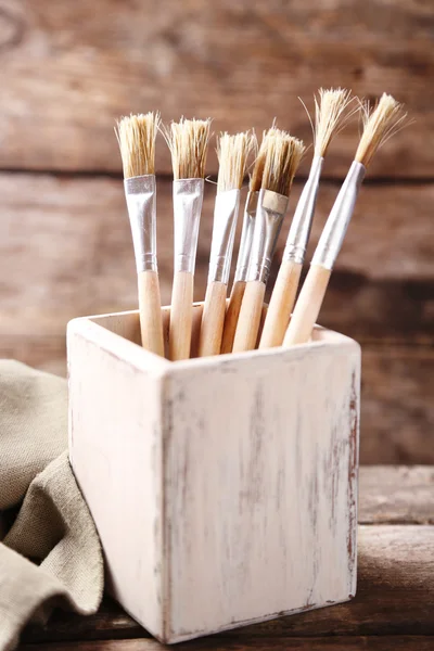 Paint brushes on old wooden background — Stock Photo, Image