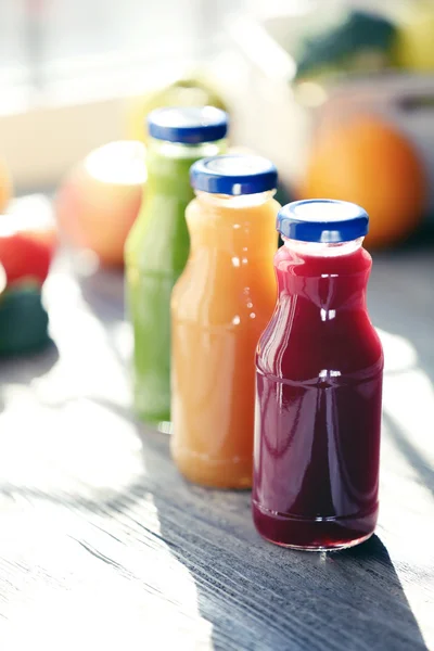 Garrafas de suco com frutas e legumes no peitoril da janela fechar — Fotografia de Stock