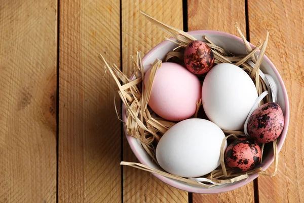 Bird colorful eggs in bowl on wooden background — Stock Photo, Image