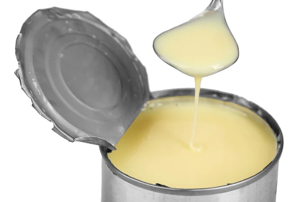Tin can of condensed milk with spoon close up — Stock Photo, Image