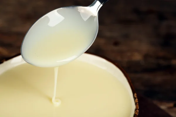 Kom met gecondenseerde melk en lepel op tafel close-up — Stockfoto