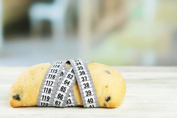 Fresh bread with measuring tape, on wooden table- diet concept — Stock Photo, Image