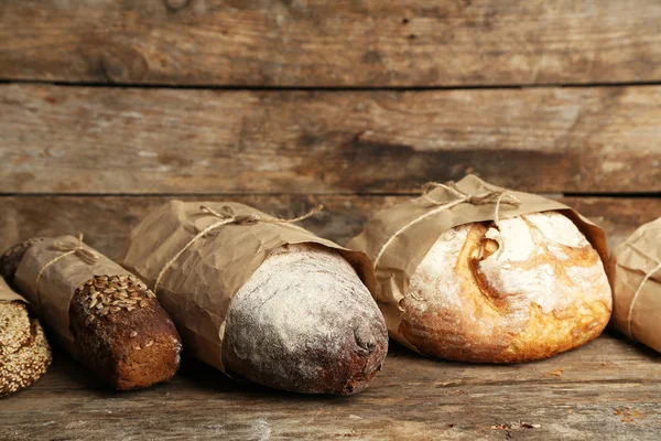 Different fresh bread, on old wooden table — Stock Photo, Image