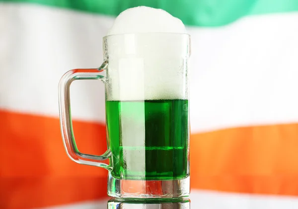 Glass of green beer on flag background — Stock Photo, Image