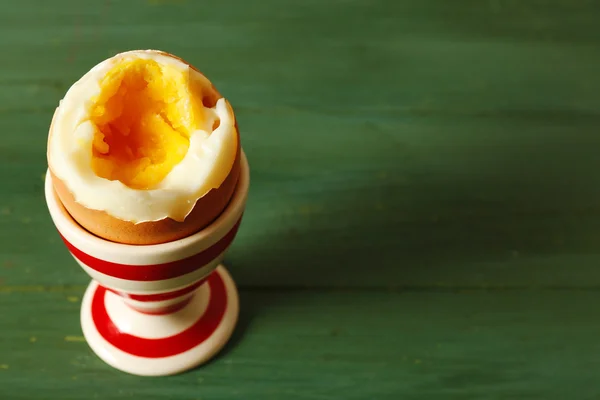 Boiled egg in holder on color wooden background — Stock Photo, Image
