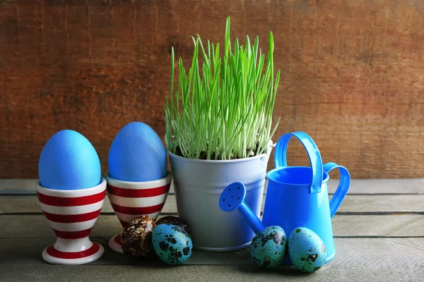 Césped verde fresco en cubo de metal pequeño y huevos de Pascua en los titulares, sobre fondo de madera —  Fotos de Stock