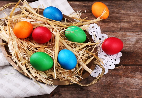 Antika ahşap plakalar arka plan üzerinde saman ile tepsi üzerinde Paskalya yumurta — Stok fotoğraf