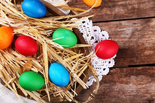 Easter eggs on tray with straw on vintage wooden planks background — Stock Photo, Image