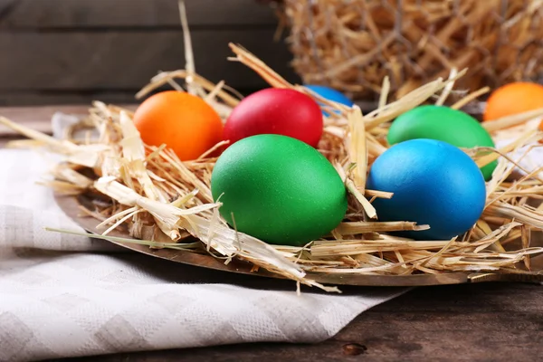 Easter eggs on tray with straw on vintage wooden planks background — Stock Photo, Image