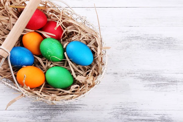 Huevos de Pascua en cesta sobre tablones de madera vintage fondo —  Fotos de Stock