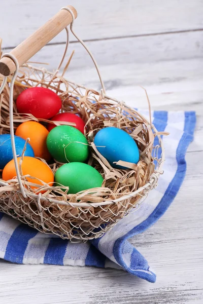 Huevos de Pascua en cesta sobre tablones de madera vintage fondo — Foto de Stock