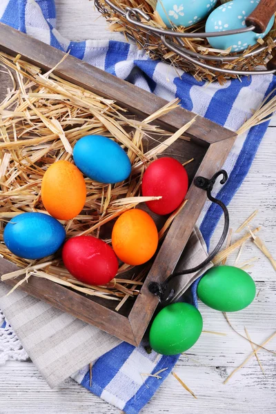 Великодні яйця на дерев'яному підносі, на барвистому фоні — стокове фото