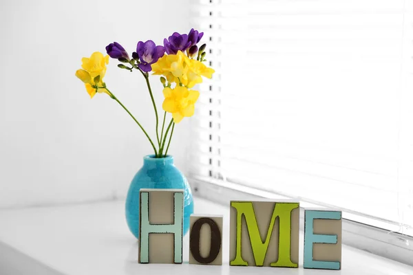 Home in colorful letters and spring flowers in light white interior — Stock Photo, Image