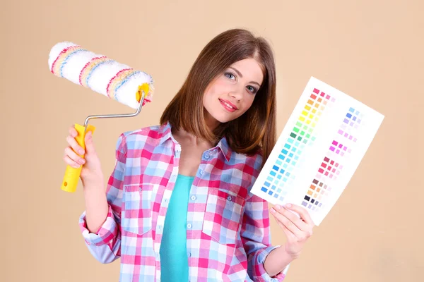 Vacker flicka med rullen och palett av färger nära vägg — Stockfoto