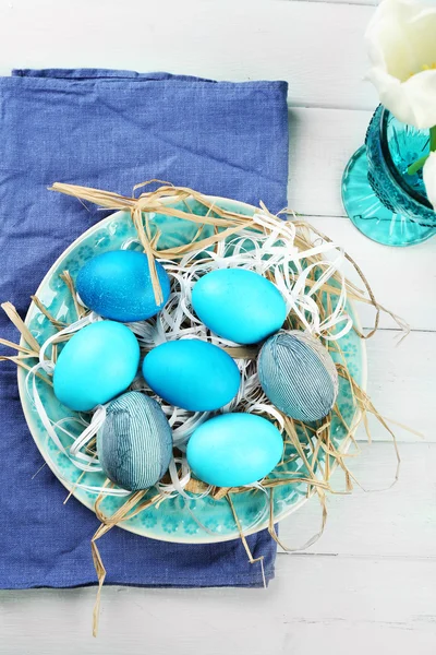 Composição de Páscoa com ovos coloridos na placa no fundo da mesa de madeira — Fotografia de Stock
