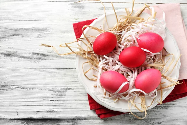 Osterkomposition mit bunten Eiern auf Teller auf Holztischhintergrund — Stockfoto