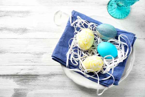 Easter composition with colorful eggs on plates on wooden table background — Stock Photo, Image