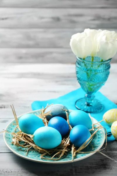 Easter composition with colorful eggs on napkin on wooden table background — Stock Photo, Image