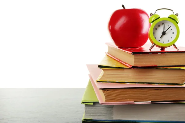 Bücher, Wecker und Apfel auf dem Schreibtisch, isoliert auf weiß — Stockfoto