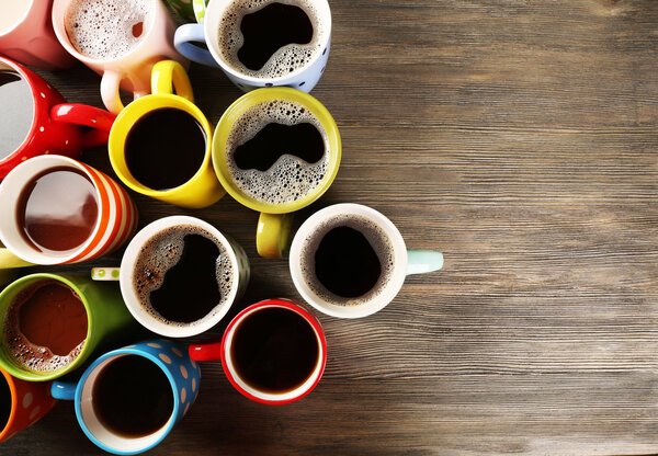 Многие чашки кофе на деревянном фоне
