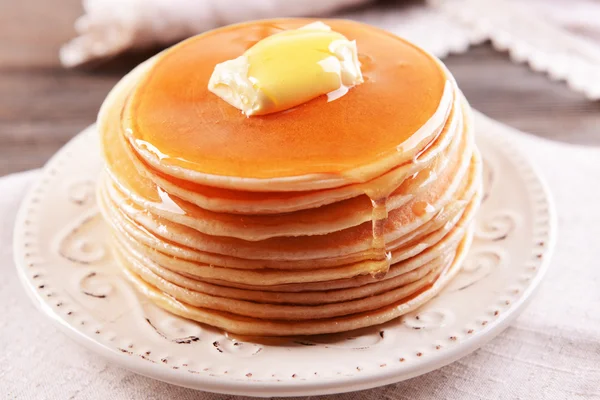 Deliciosos panqueques con miel en el plato en primer plano de la mesa — Foto de Stock