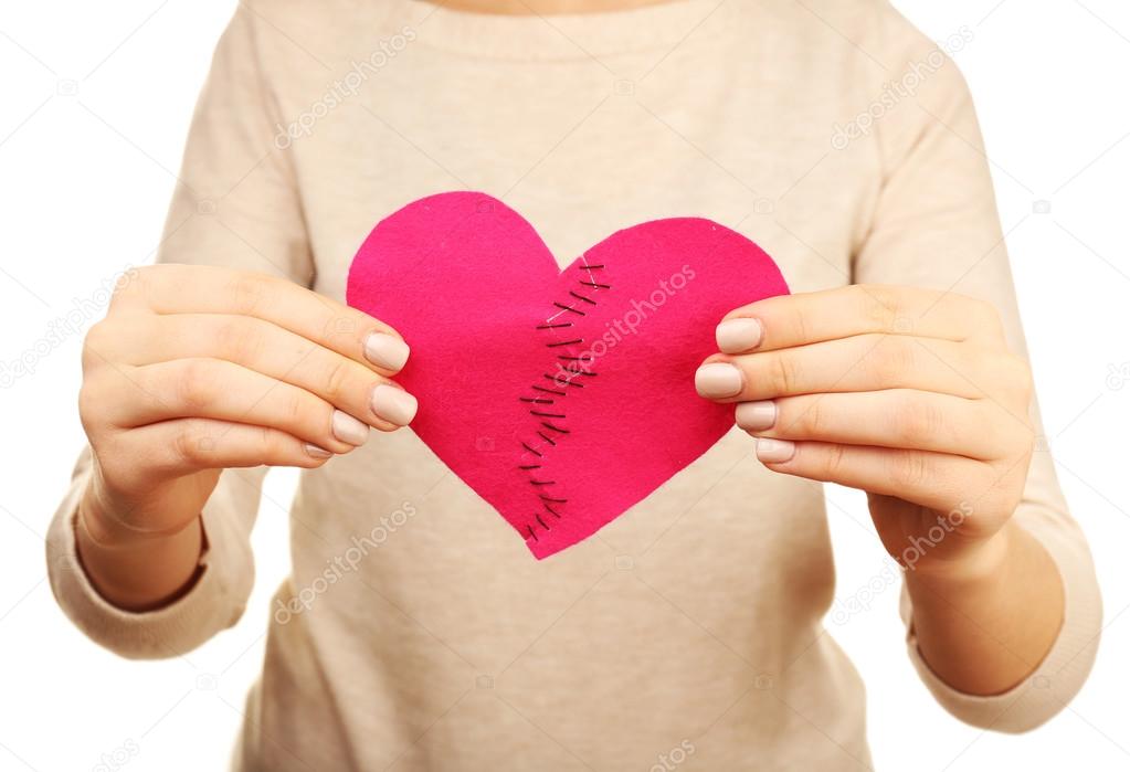 Woman holding broken heart stitched from two pieces close up
