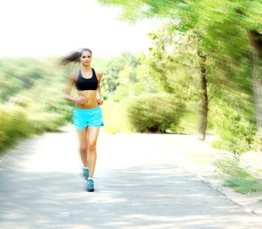 Genç bir kadın parkta koşuyor.