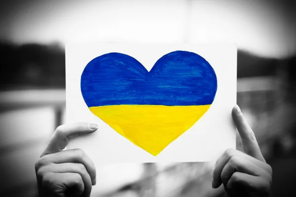 Ruce držící papírové srdce s malovanými vlajka Ukrajiny — Stock fotografie