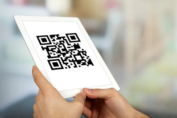 Hand holding tablet with QR code on screen