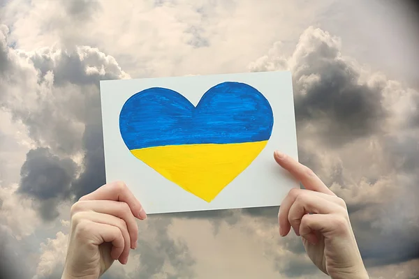 Mãos segurando coração de papel com bandeira da Ucrânia pintada — Fotografia de Stock