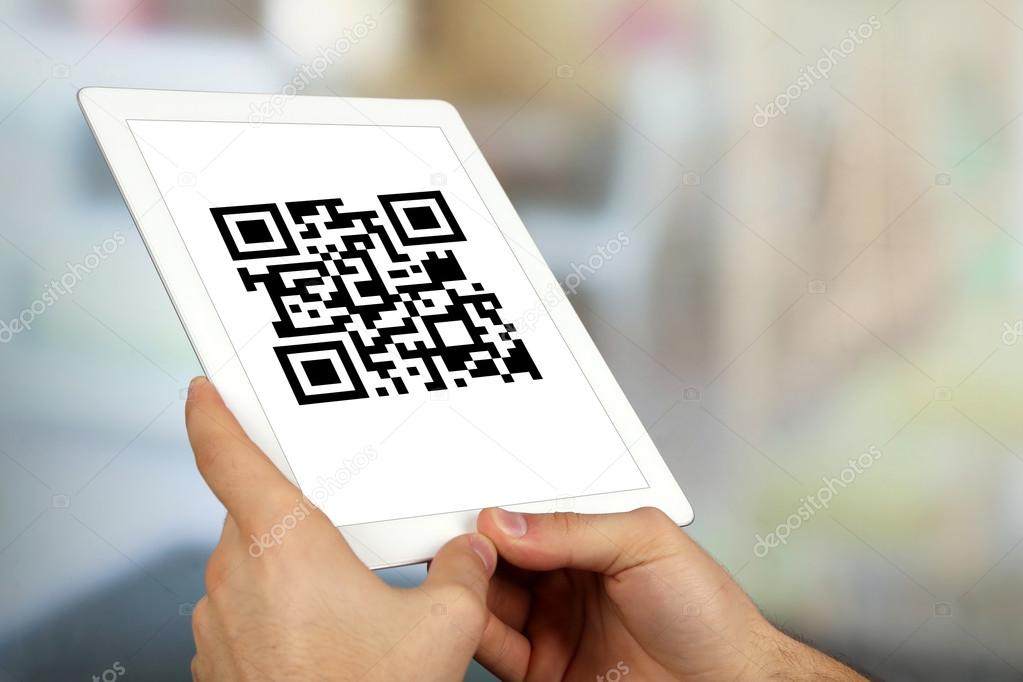 Hand holding tablet with QR code on screen