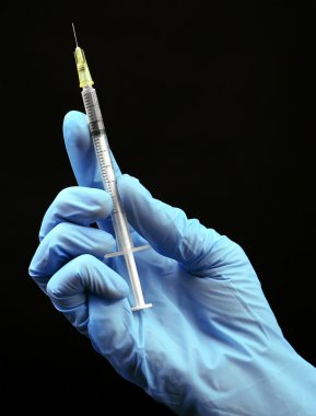 Ellerinde eldiven siyah arka plan üzerine şırınga