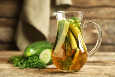 Ahşap masa üzerinde taze organik salatalık suyu ile cam ibrik