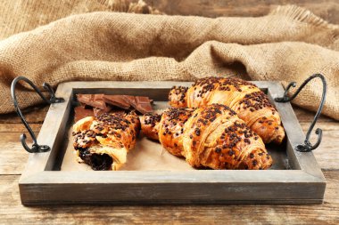 Taze ve lezzetli kruvasan çul arka plan üzerinde ahşap tepsi çikolata ile