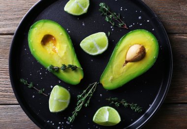 Ahşap masa arka plan üzerinde metal plaka üzerinde avokado kireç ve bitki ile dilimlenmiş