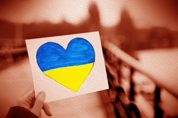 Hände halten Papierherz mit bemalter ukrainischer Flagge — Stockfoto