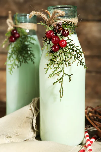 Botellas de leche fresca con decoración natural, sobre fondo de madera — Foto de Stock