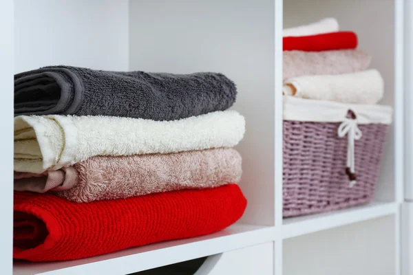 Kleurrijke handdoeken met rieten mand op plank van rack achtergrond — Stockfoto
