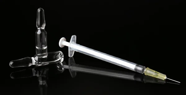 Ampules with syringe on black background — Stock Photo, Image