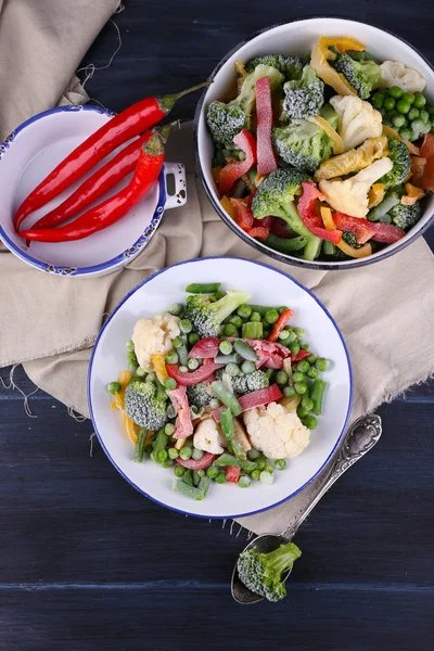 Замороженные овощи на тарелке на салфетке, на деревянном фоне стола — стоковое фото