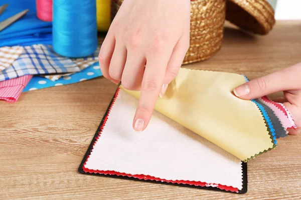 Kleurrijke stofstalen in vrouwelijke handen op houten tafel achtergrond — Stockfoto