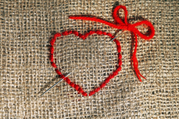 Linen canvas with red heart embroidered on it, close-up