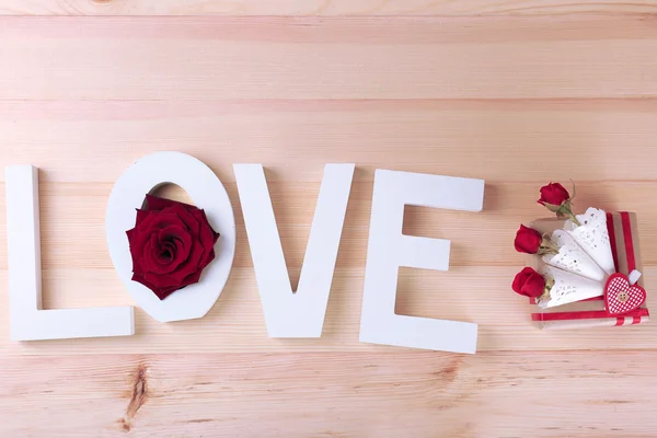 Hermosas rosas con palabra AMOR y caja de regalo sobre tablones de madera fondo — Foto de Stock